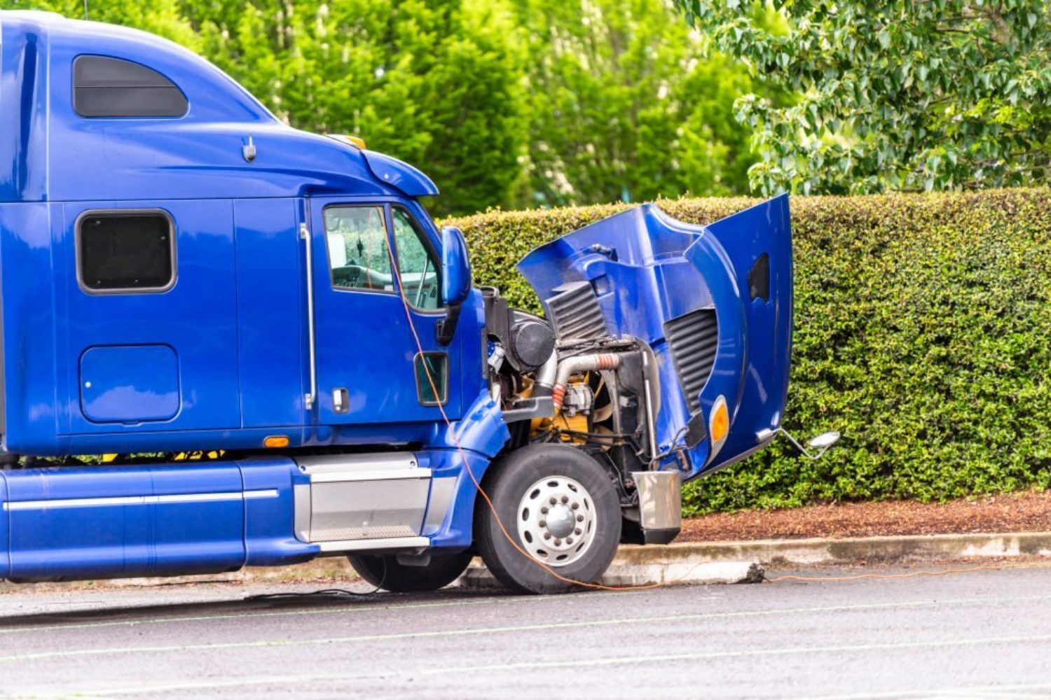 Broken American industrial grade freight transportation blue big rig semi truck tractor with an open hood stands on the truck stop parking lot waiting for mobile repair on site