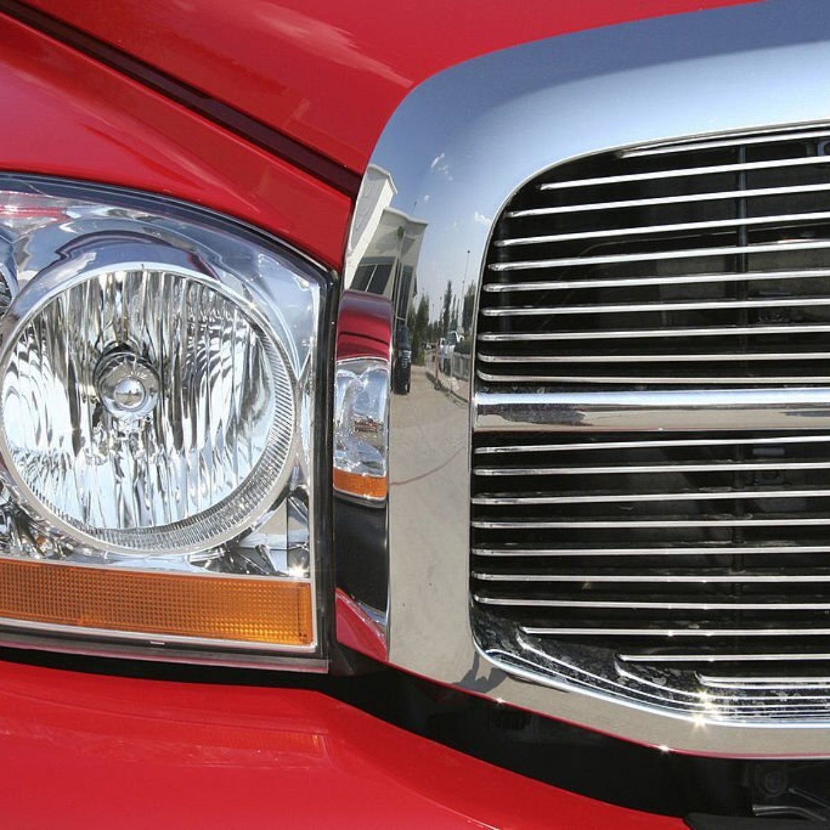 Front headlight and grill of a Dodge red truck.